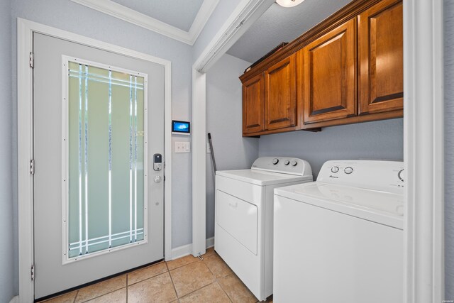 clothes washing area featuring light tile patterned floors, washing machine and dryer, baseboards, cabinet space, and crown molding