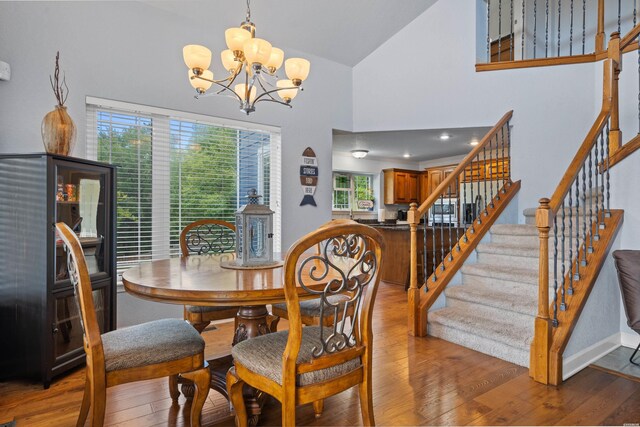 dining room featuring a chandelier, high vaulted ceiling, stairway, and wood finished floors