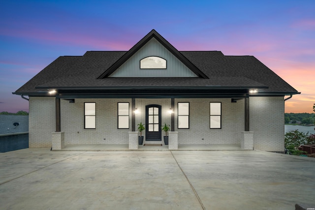 view of front of home featuring brick siding and a shingled roof