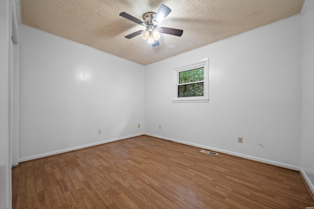 spare room with a ceiling fan, a textured ceiling, visible vents, and wood finished floors