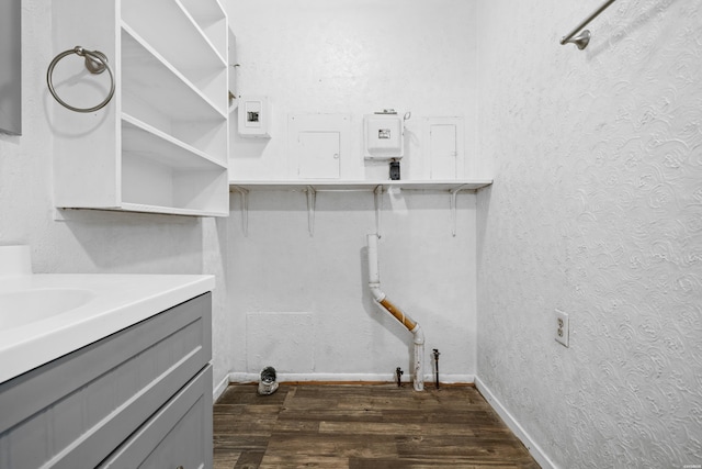 laundry area with dark wood-style flooring, a textured wall, baseboards, and laundry area