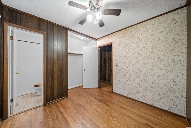 unfurnished bedroom with light wood-style flooring, ornamental molding, ceiling fan, and a textured ceiling