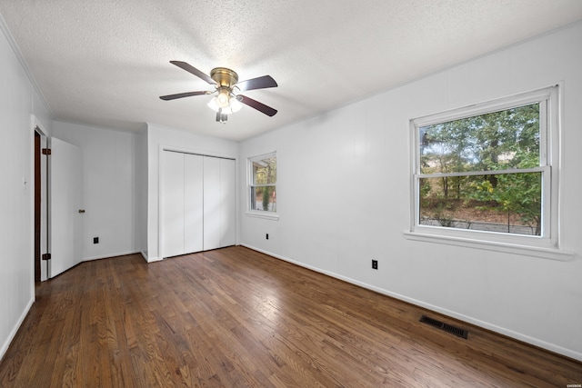 unfurnished bedroom with a closet, visible vents, dark wood finished floors, and a textured ceiling