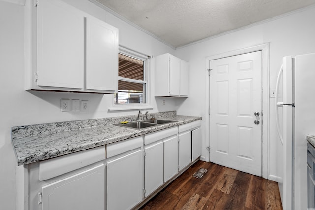 kitchen featuring dark wood-style flooring, freestanding refrigerator, a textured ceiling, white cabinetry, and a sink