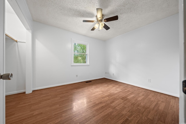 spare room featuring a textured ceiling, baseboards, and wood finished floors