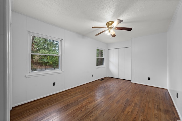 spare room featuring dark wood-style floors, a textured ceiling, and a healthy amount of sunlight