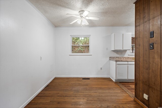 unfurnished dining area featuring baseboards, a ceiling fan, dark wood finished floors, and a textured ceiling