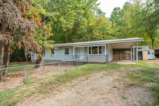 ranch-style home featuring a carport, metal roof, fence, and dirt driveway