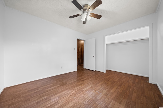 unfurnished bedroom with a textured ceiling, a closet, wood finished floors, and baseboards