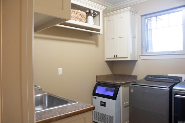 clothes washing area with crown molding, cabinet space, a sink, and separate washer and dryer