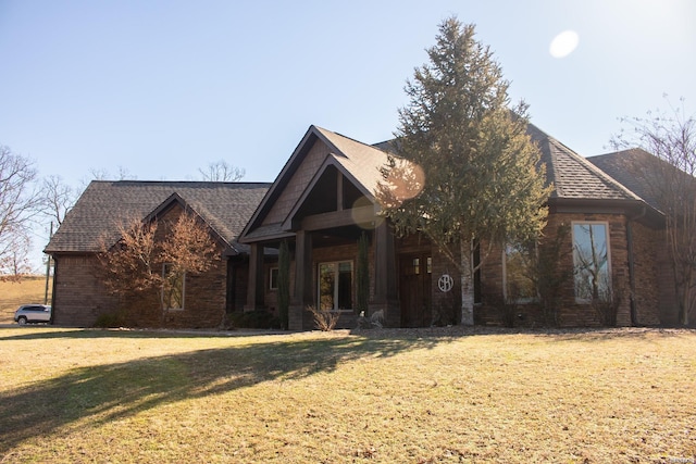 view of front of property featuring brick siding, a front yard, and a shingled roof