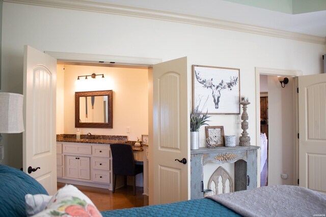 bedroom featuring a sink, built in desk, crown molding, and wood finished floors