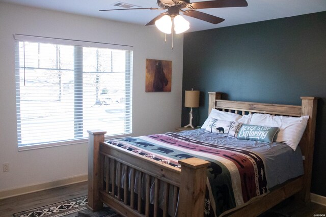 bedroom featuring a ceiling fan, visible vents, baseboards, and dark wood-type flooring