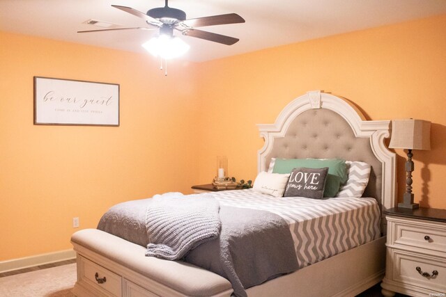 bedroom featuring light colored carpet, a ceiling fan, and baseboards