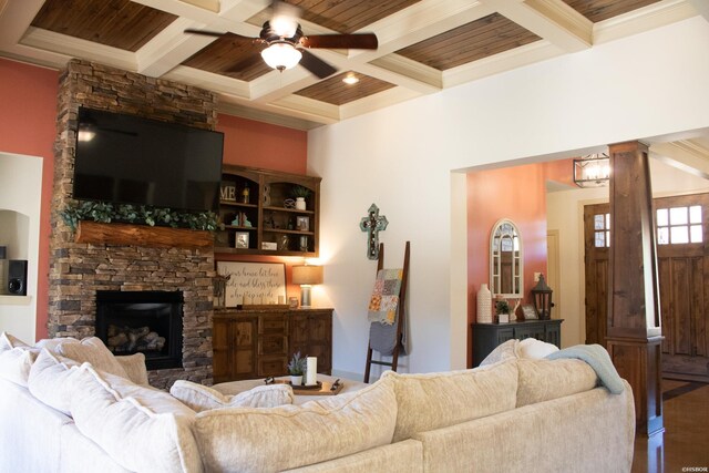 living room with a ceiling fan, wood finished floors, ornate columns, a fireplace, and beam ceiling