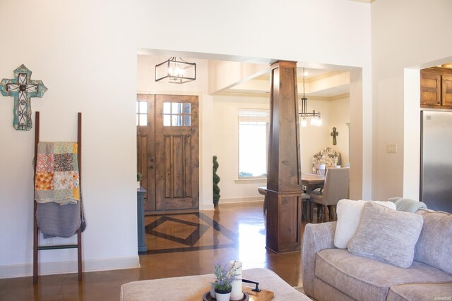 entryway featuring decorative columns, baseboards, and an inviting chandelier