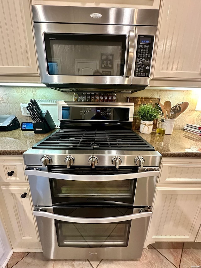 room details featuring dark stone counters, stainless steel appliances, and decorative backsplash