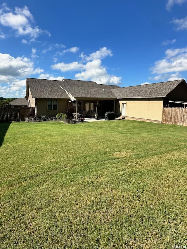 back of house featuring a patio, a lawn, fence, and stucco siding