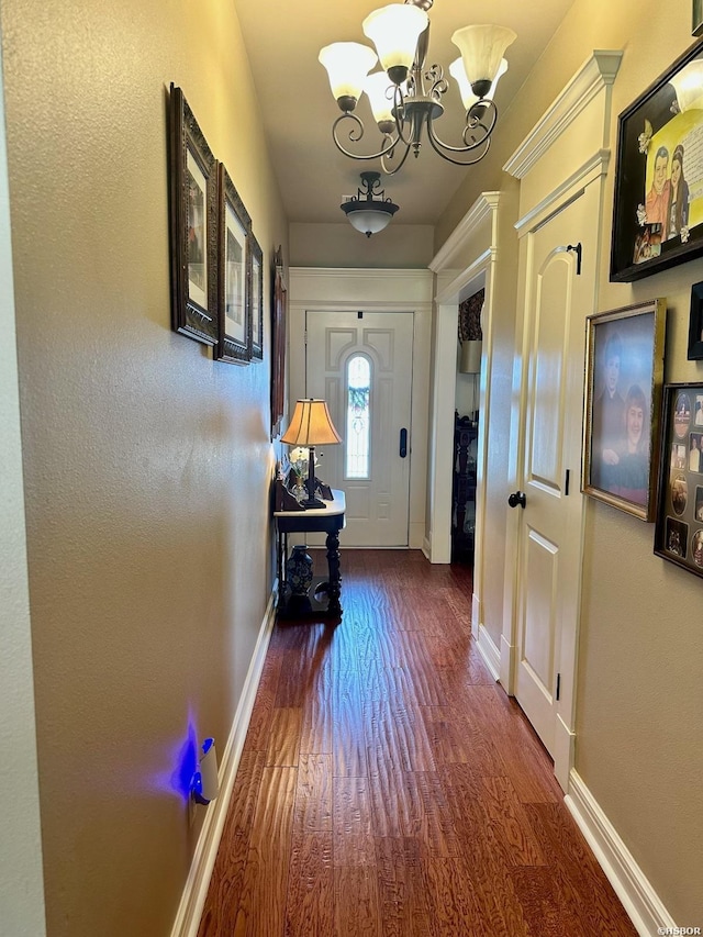 hall with a chandelier, baseboards, and wood finished floors