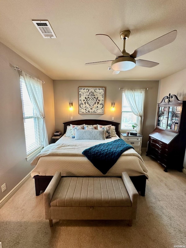 bedroom featuring multiple windows, visible vents, and light colored carpet