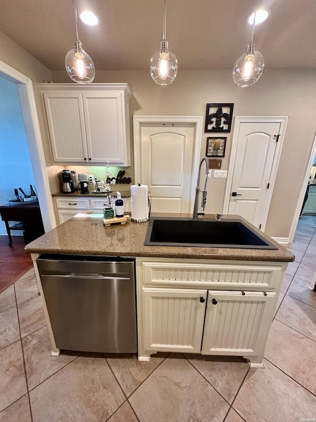 kitchen featuring white cabinets, decorative light fixtures, a kitchen island with sink, stainless steel dishwasher, and a sink