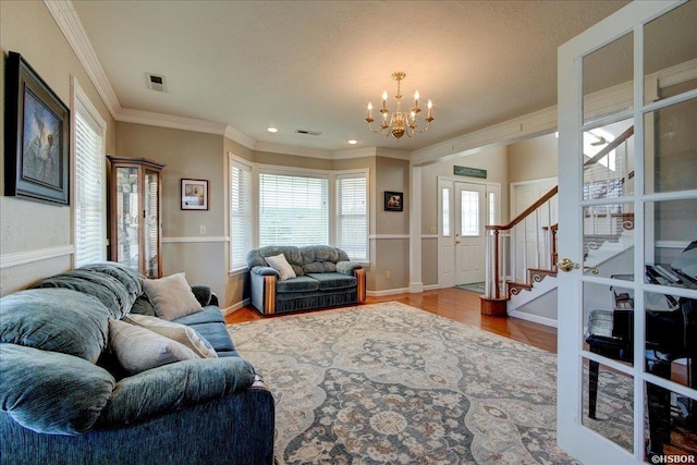 living room featuring ornamental molding, stairway, an inviting chandelier, and wood finished floors