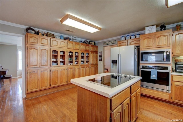 kitchen featuring stainless steel appliances, light countertops, a kitchen island, and ornamental molding