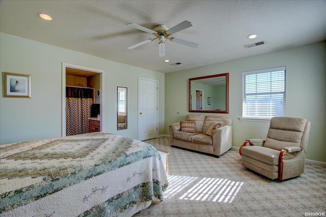 bedroom featuring light colored carpet, visible vents, a textured ceiling, and baseboards