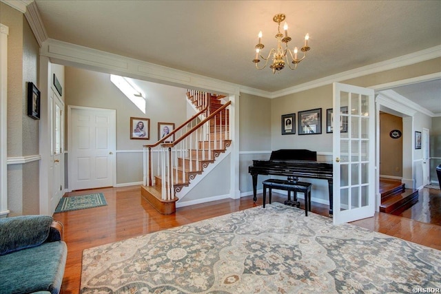 entrance foyer featuring baseboards, stairway, wood finished floors, an inviting chandelier, and crown molding