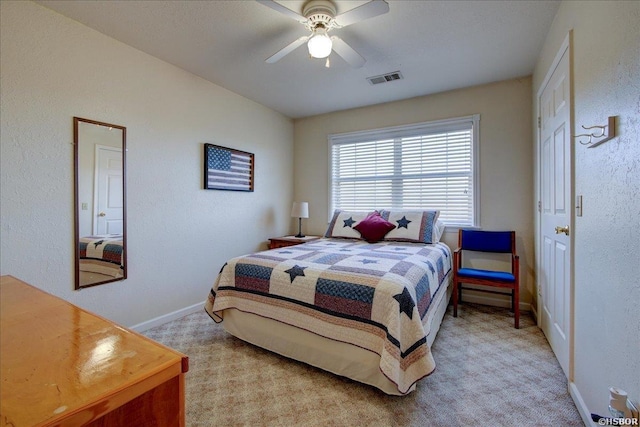 bedroom with a ceiling fan, light colored carpet, visible vents, and baseboards