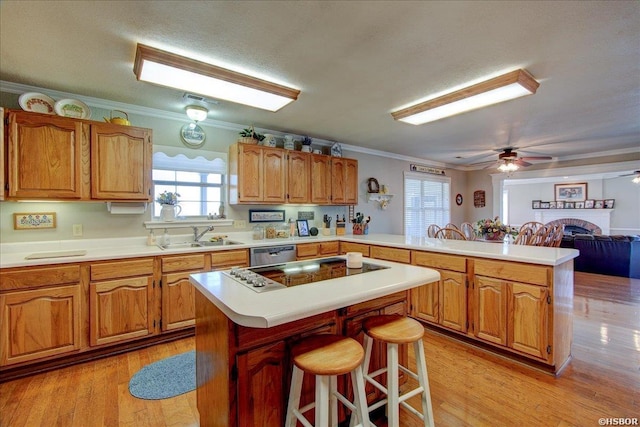 kitchen featuring ornamental molding, a breakfast bar area, a center island, a peninsula, and light countertops