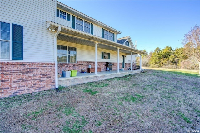 exterior space with brick siding, a front lawn, and a patio area