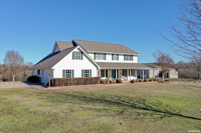 view of front of property featuring driveway, covered porch, an attached garage, and a front yard