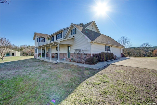 view of front of house with an attached garage, a front lawn, a porch, and concrete driveway