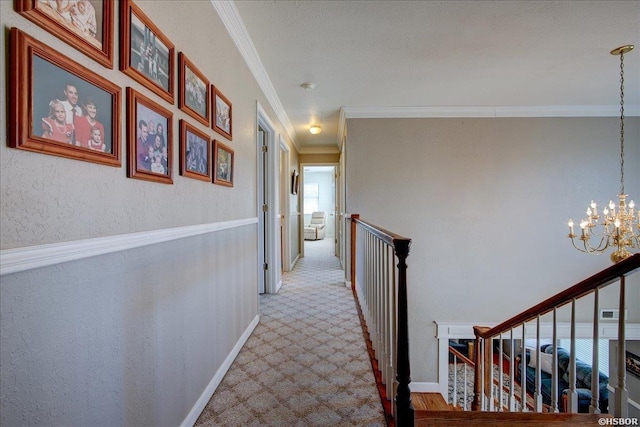 hallway with baseboards, a textured wall, light colored carpet, crown molding, and a notable chandelier