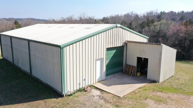 view of pole building featuring a lawn, driveway, and a wooded view