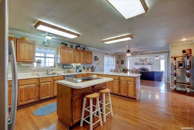 kitchen featuring appliances with stainless steel finishes, a center island, light countertops, and a peninsula