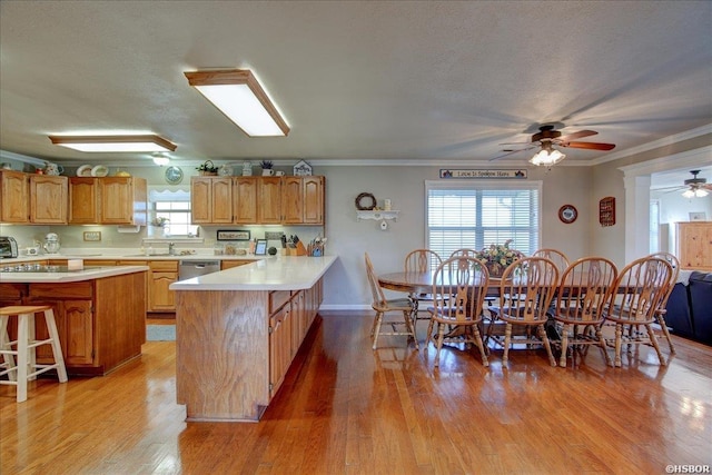 kitchen featuring light countertops, ornamental molding, a peninsula, and a healthy amount of sunlight