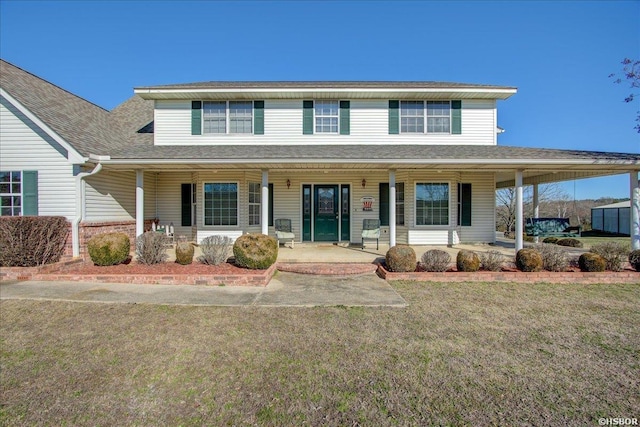 view of front facade with a shingled roof, a porch, and a front lawn