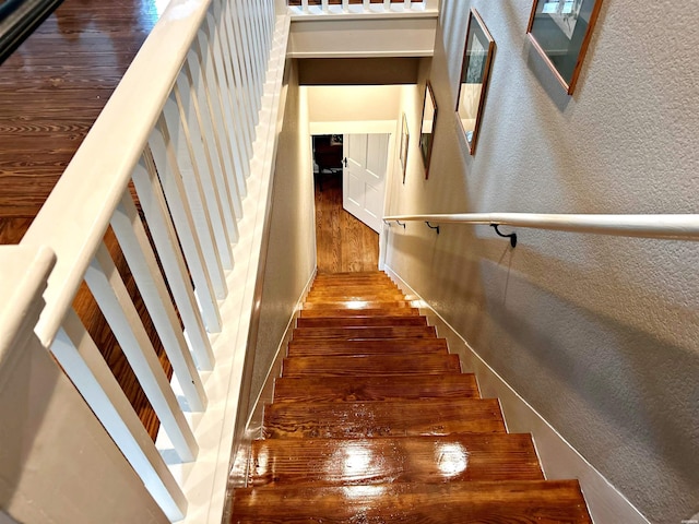 stairs featuring a textured wall and wood finished floors