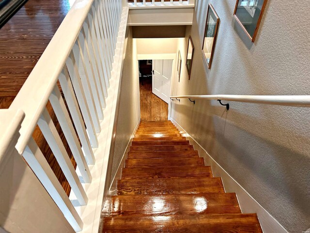 stairs featuring a textured wall and wood finished floors