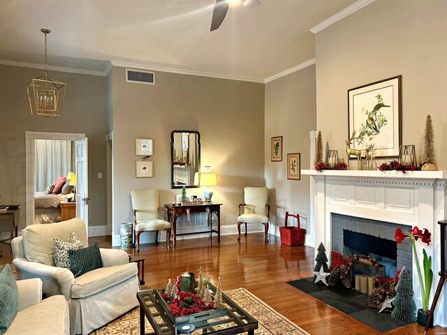 living room with a fireplace, visible vents, ornamental molding, wood finished floors, and baseboards