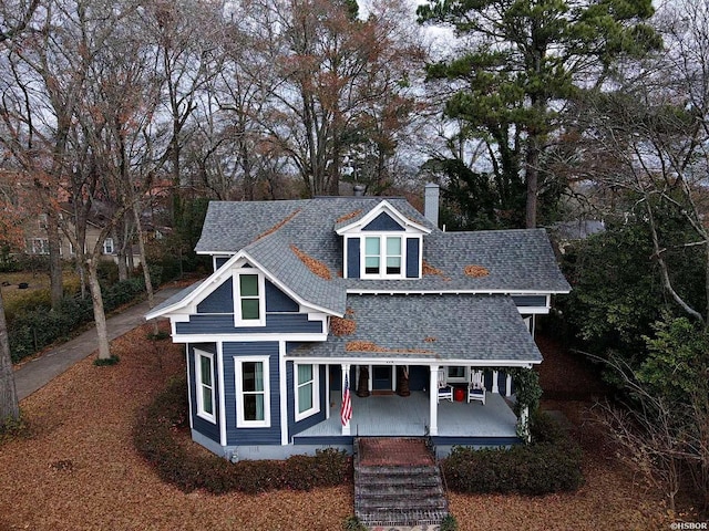 view of front facade with crawl space, a chimney, a porch, and roof with shingles