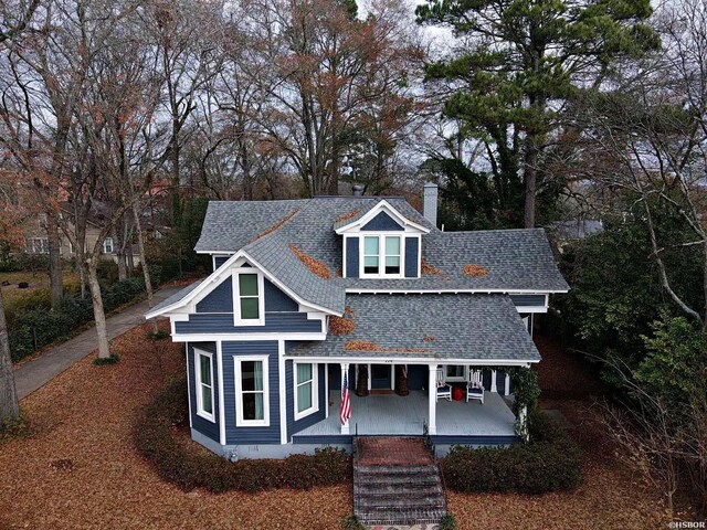 view of front facade with crawl space, a chimney, a porch, and roof with shingles