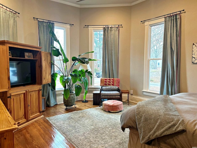 bedroom featuring baseboards, ornamental molding, and wood finished floors