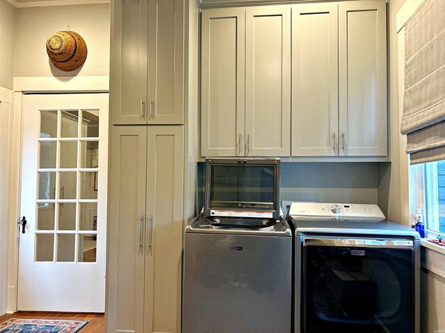 laundry room with cabinet space, washer and dryer, and wood finished floors