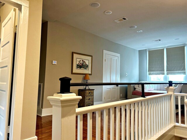 corridor featuring baseboards, visible vents, wood finished floors, an upstairs landing, and recessed lighting