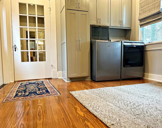 kitchen with light wood-type flooring, washing machine and dryer, and gray cabinetry