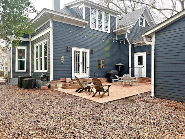 back of property with entry steps, a chimney, and a patio area