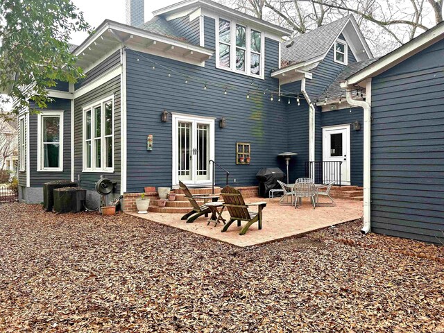 back of property with entry steps, a chimney, and a patio area